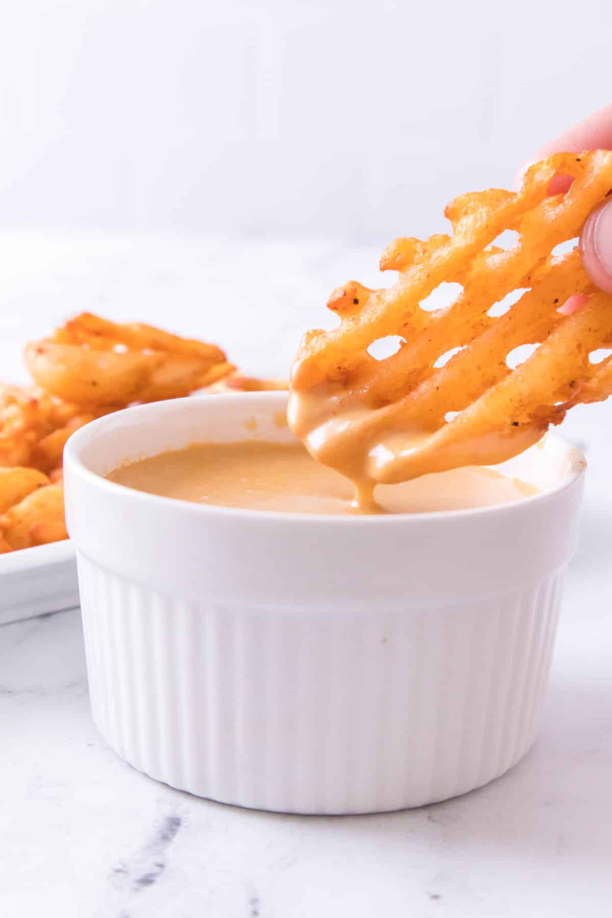 platter of waffle fries and a bowl of Chick-Fil-A dipping sauce.