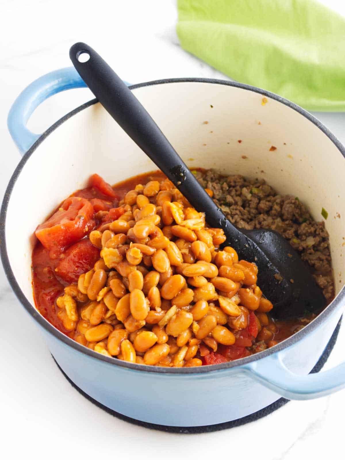 beans and diced tomatoes to ground beef in an enameled dutch oven.