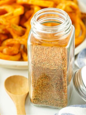 French fry spice in a spice jar with curly fries in the background.
