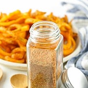French fry spice in a spice jar with curly fries in the background.