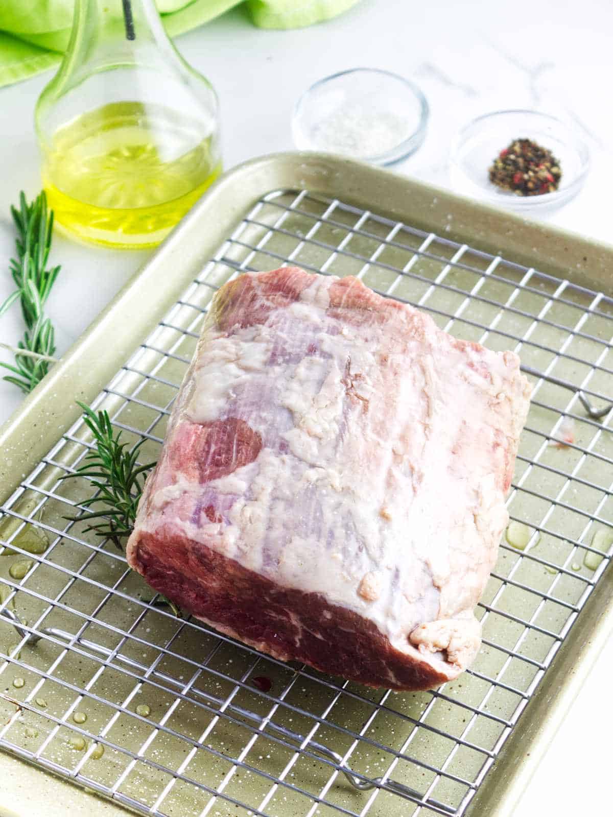 beef roast, olive oil, salt, peppercorns, and rosemary on a white background.