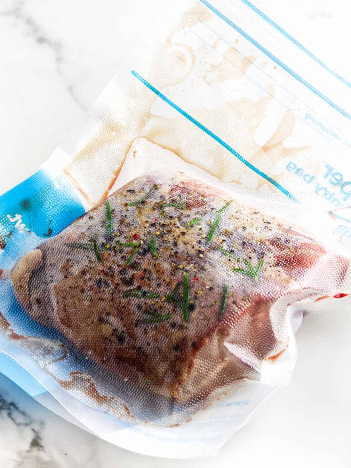 raw beef roast in a sous vide bag with rosemary and seasonings.