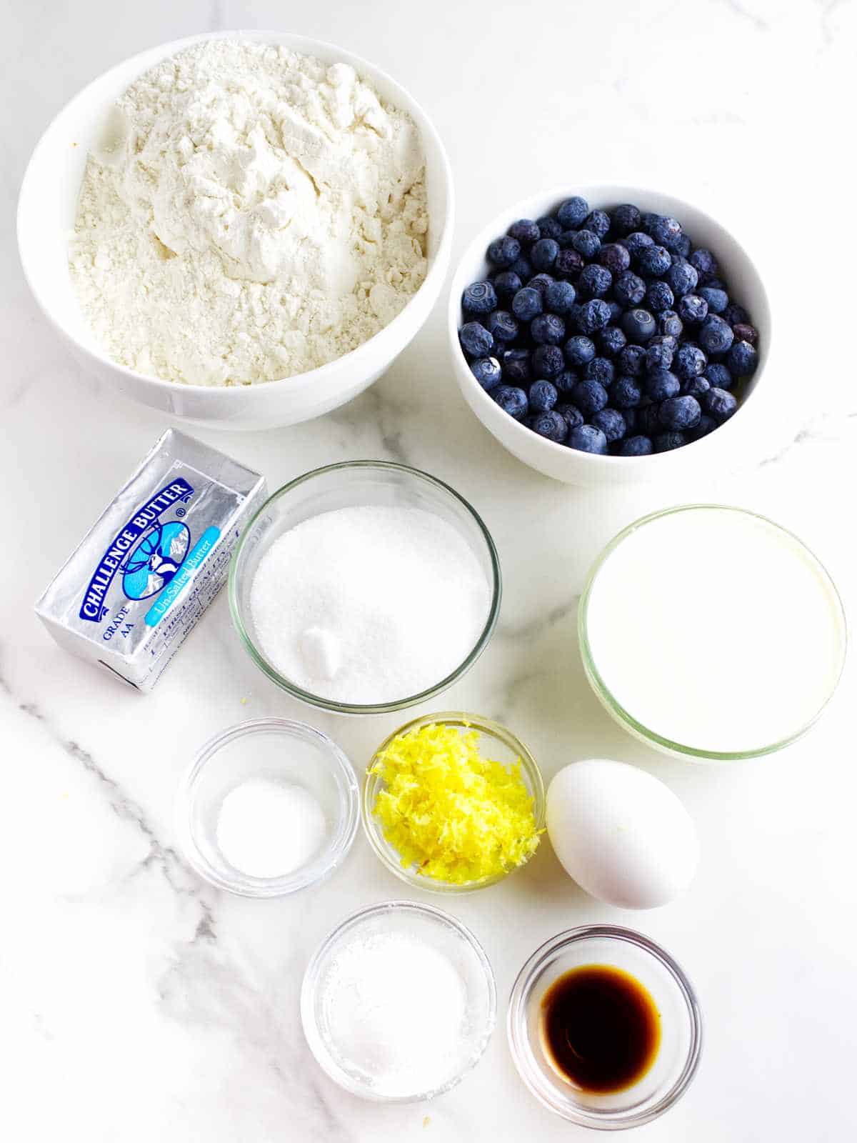 ingredients for blueberry scones on a white marble background.