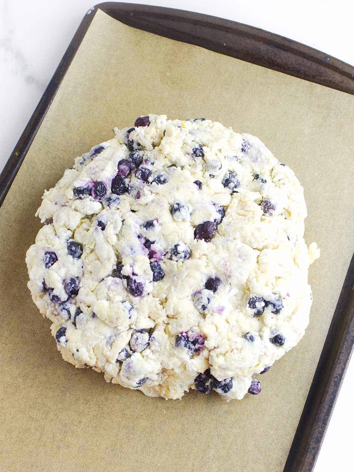 blueberry dough disc on a parchment paper lined baking sheet.