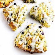 Icing drizzled over copycat starbucks blueberry scones on a white marble background.