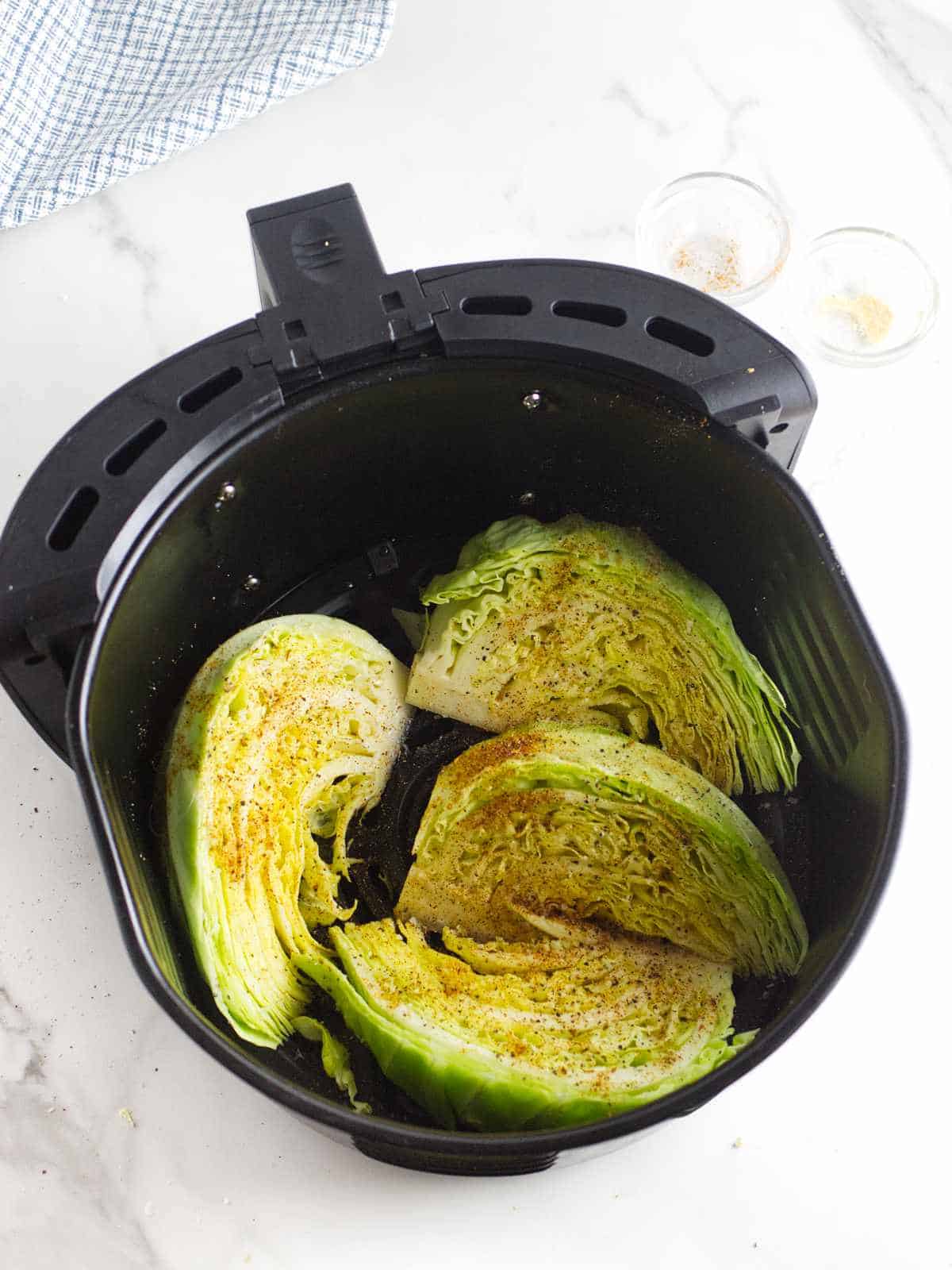 air fryer basket with seasoned cabbage wedges.