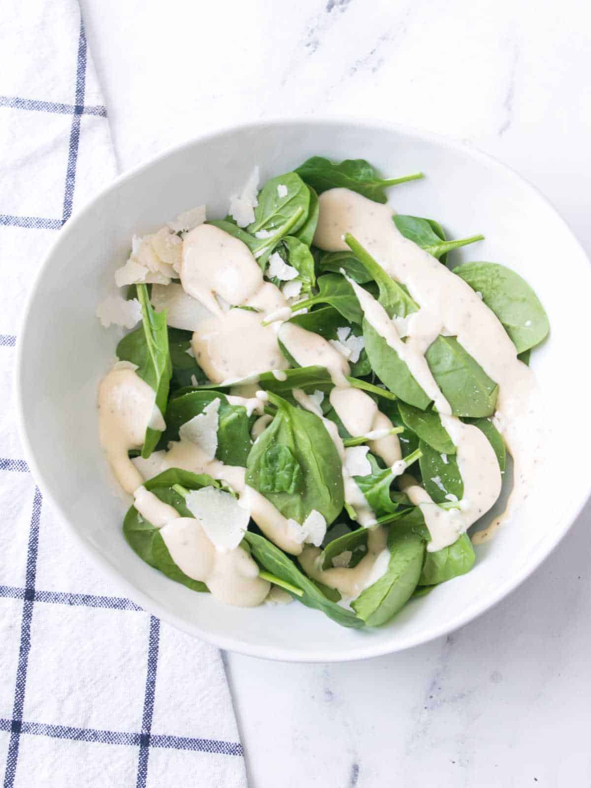 crisp romaine and spinach in a bowl with dressing.