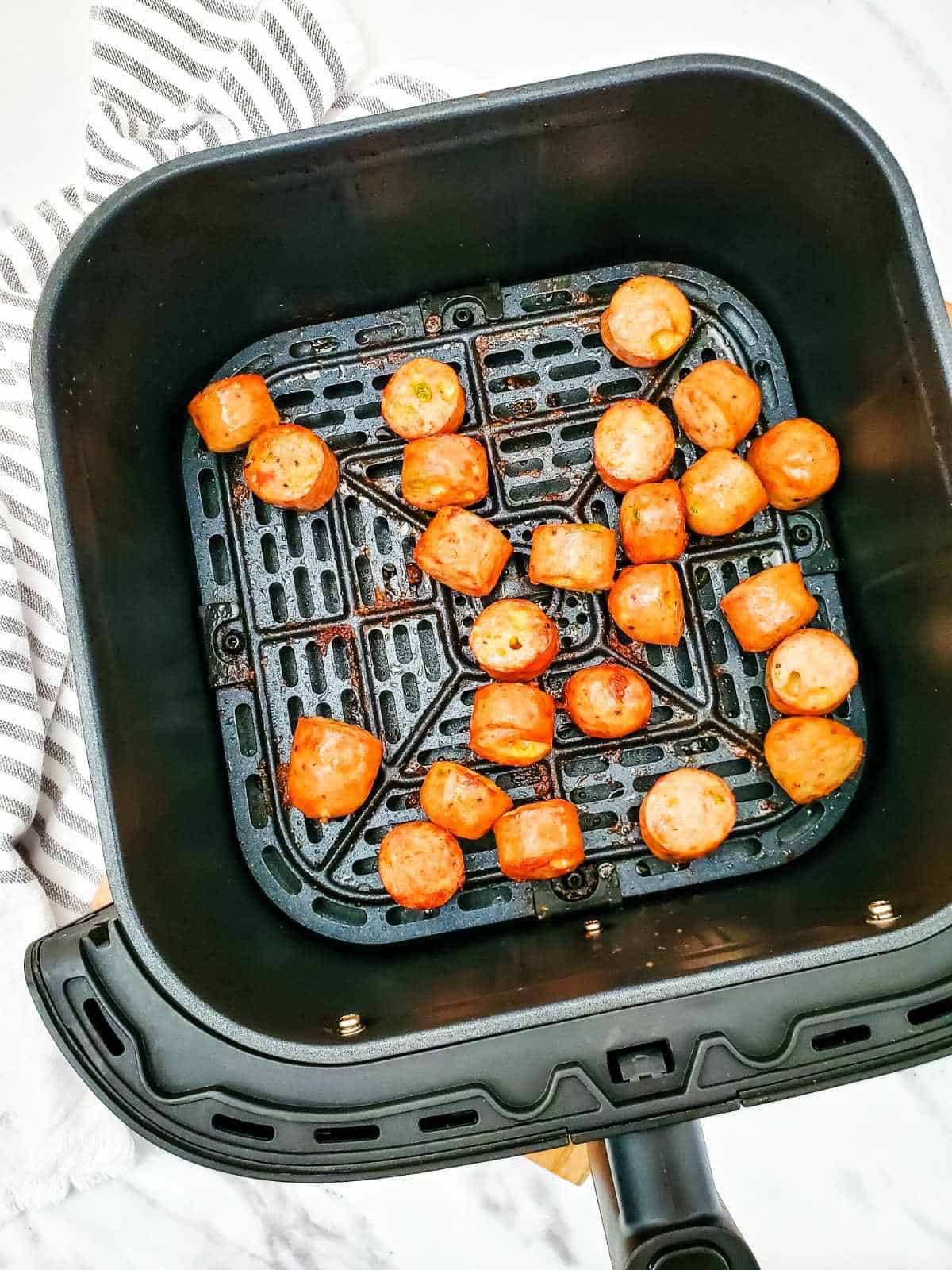 air fryer basket with cooked sausage bites inside.