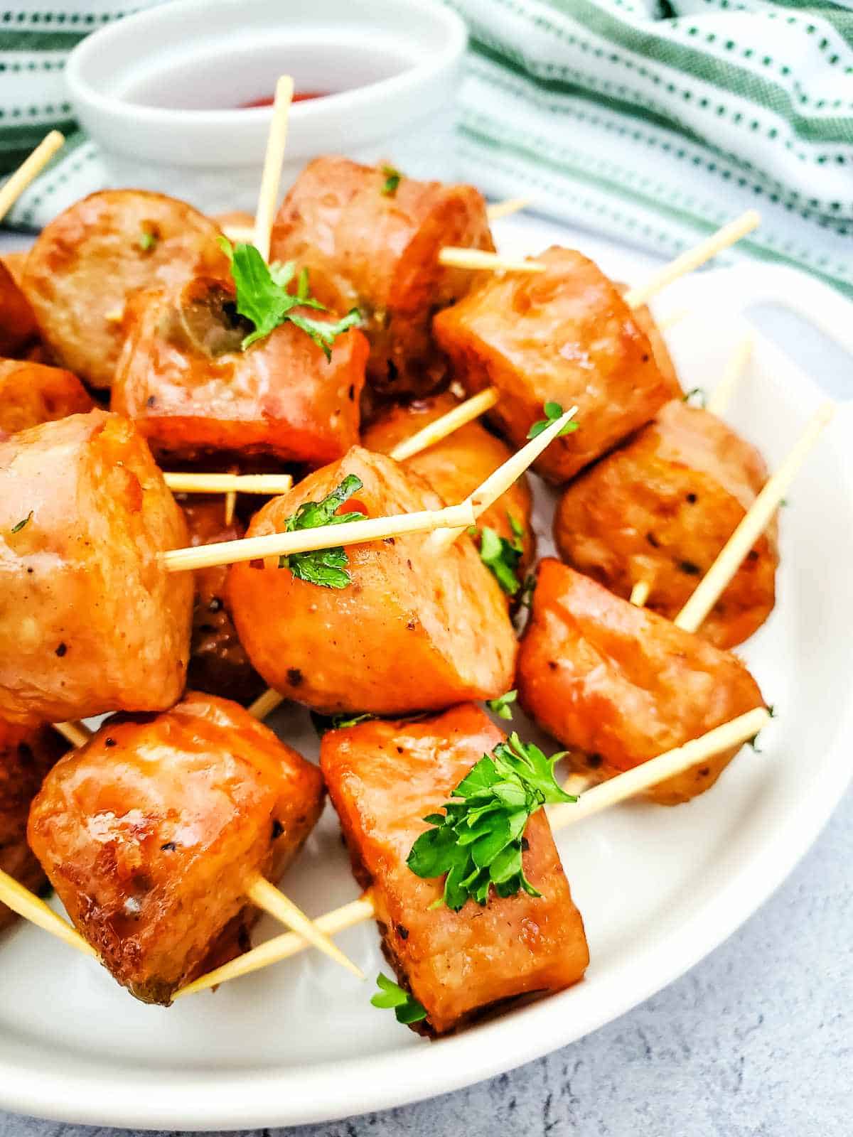 Plate of toothpick speared chicken sausage bites with parsley garnish.