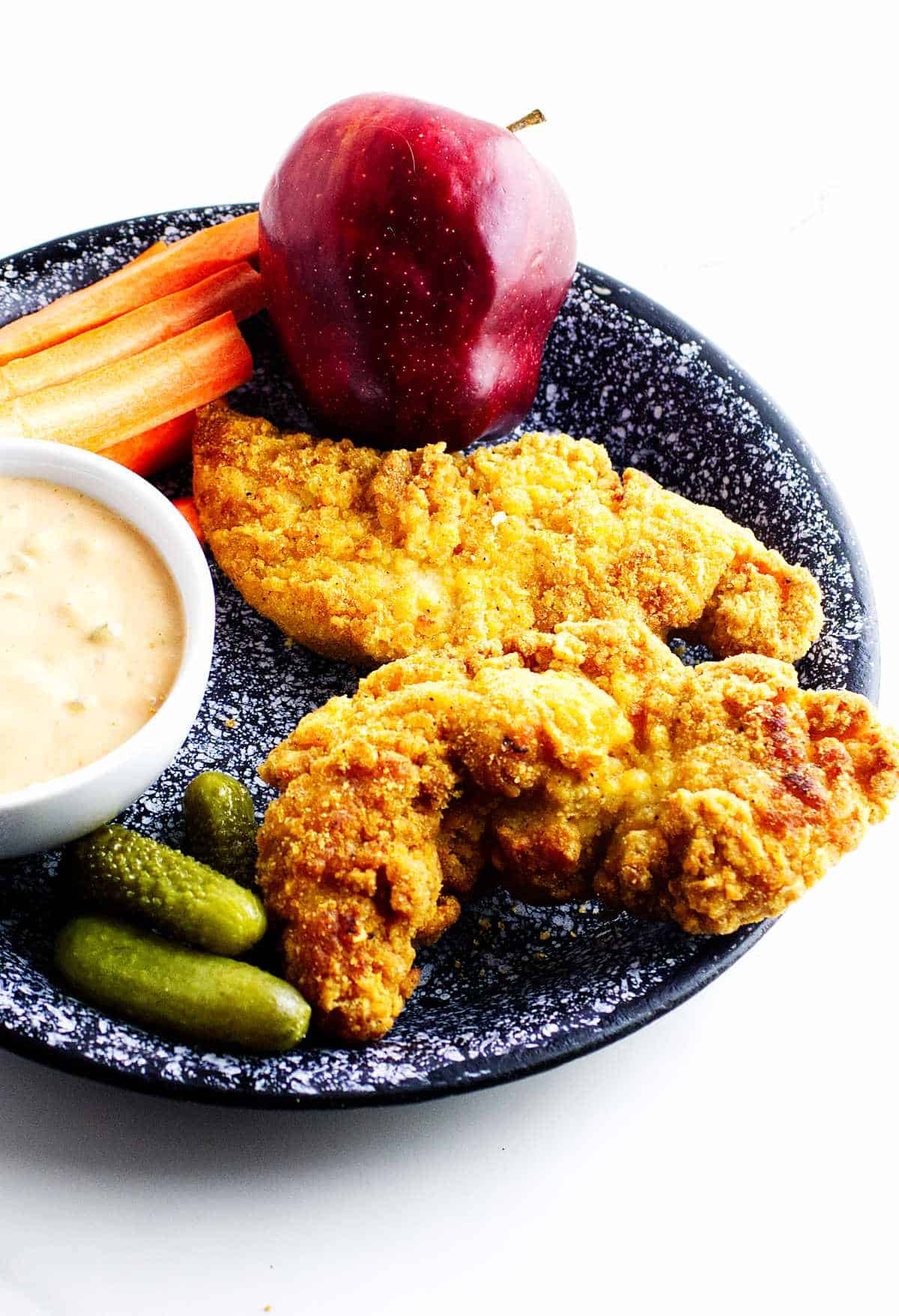 frozen chicken tenders in air fryer on a plate with dip.