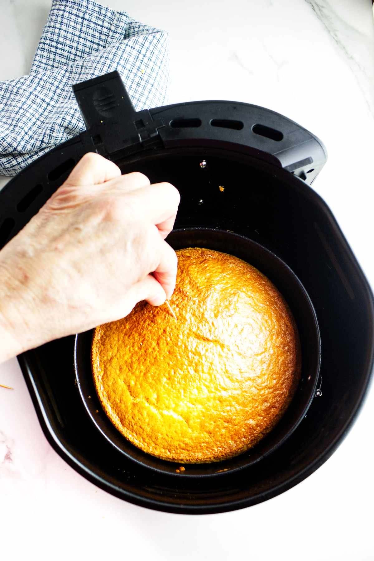 toothpick testing doneness of baked cornbread in air fryer basket.