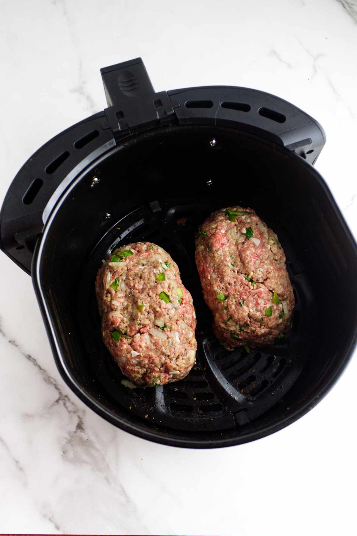 two small meatloaves in an air fryer basket ready to cook.