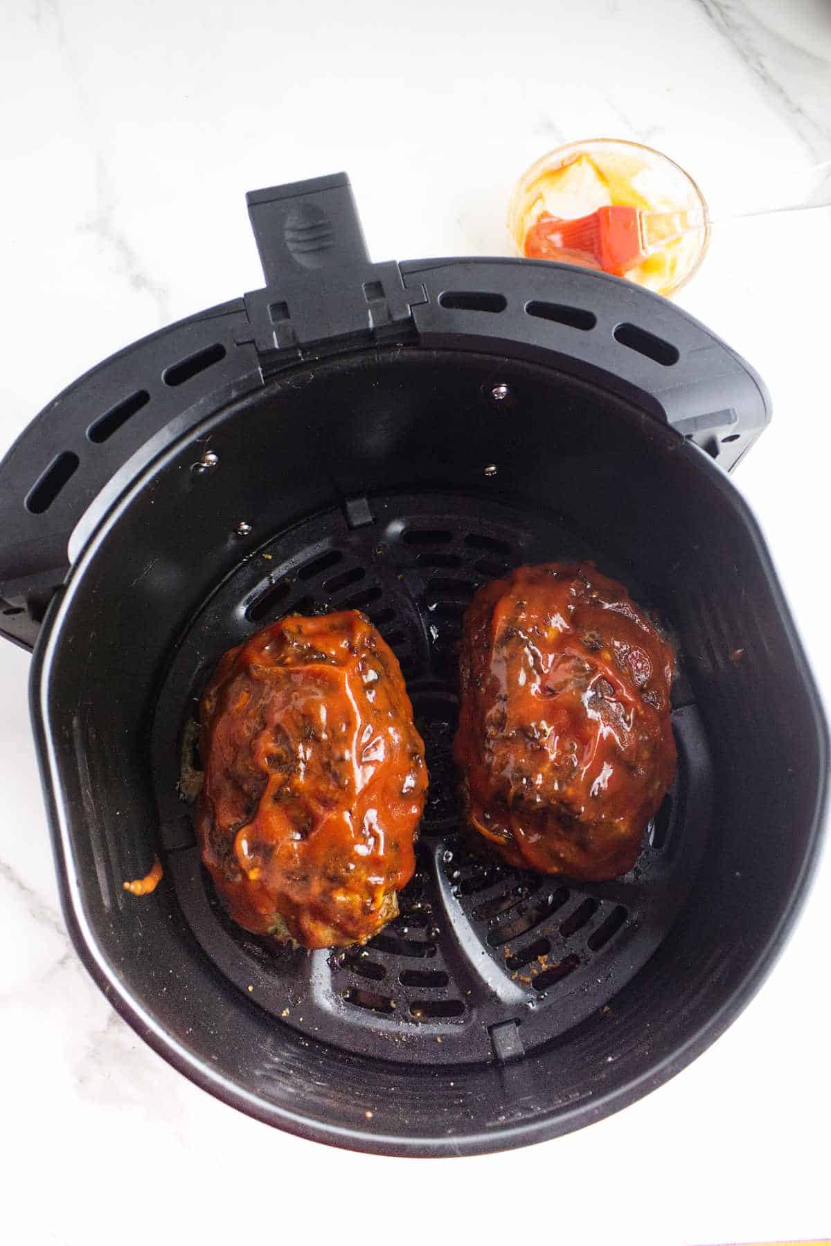 meatloaves glazed with catsup in an airfryer basket.