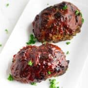 platter with two parsley garnished, catsup glazed meatloaves.