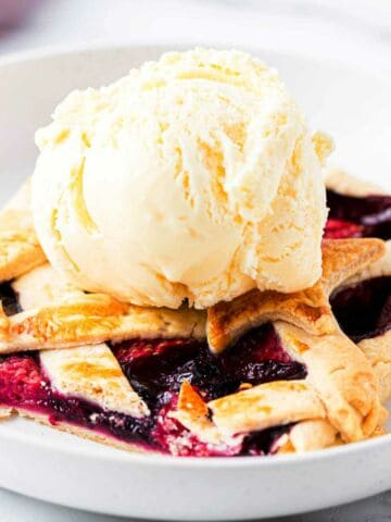 coop of vanilla ice cream on a piece of triple berry slab pie in a bowl.