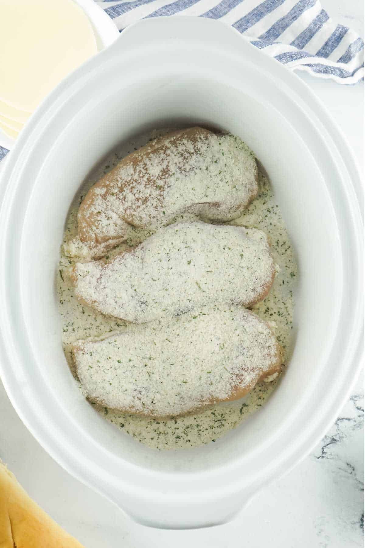 Ranch salad dressing sprinkled on top of chicken in a crockpot.