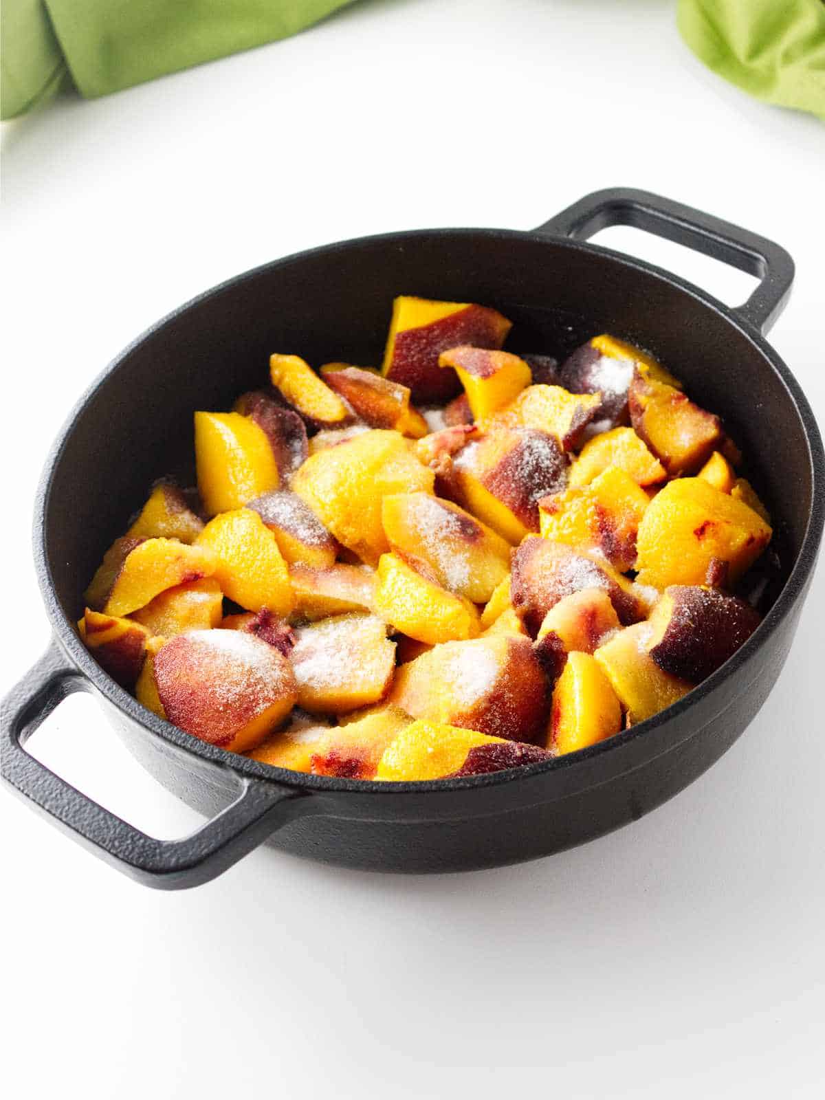 sliced peaches with sugar on top in a cast iron Lodge skillet.