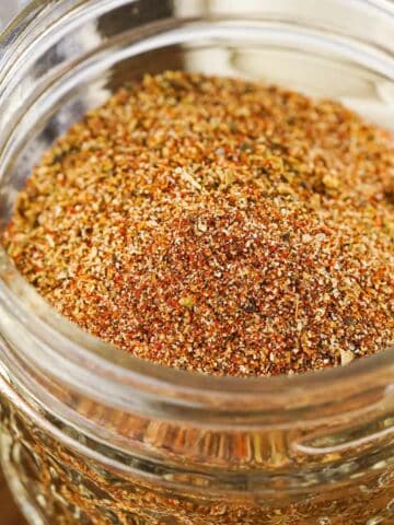 clear glass bowl of mixed spice blend with red spice in background.