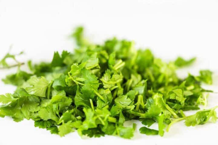 Chopped fresh cilantro on a white cutting board.