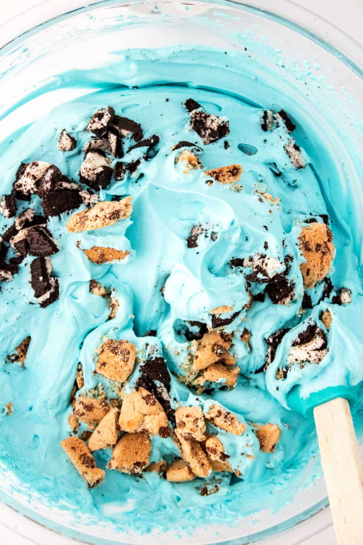 Folding crushed cookies into blue cream mixture.