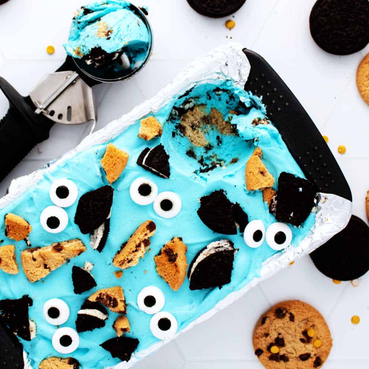 Cookie Monster ice cream on a white background with a scoop nearby.