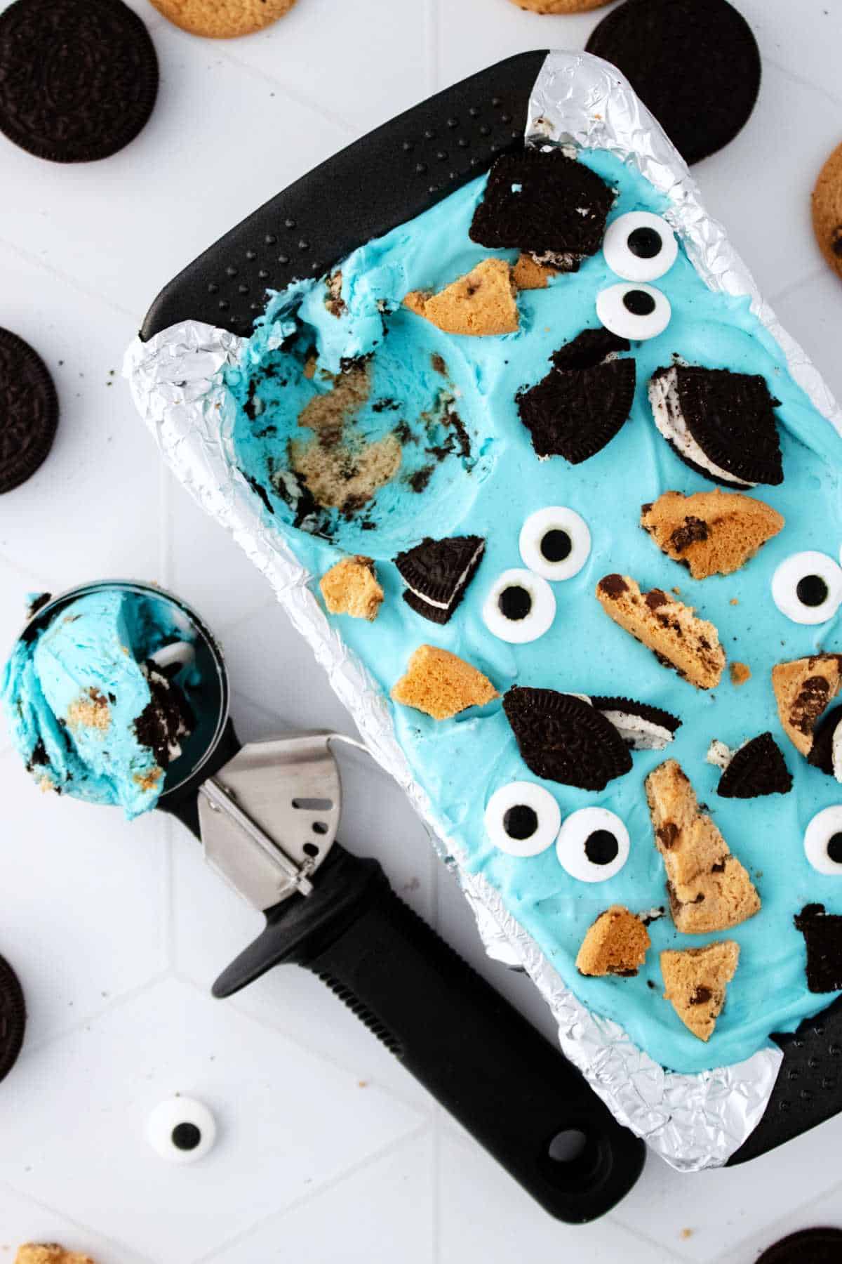 Cookie Monster ice cream on a white background with a scoop nearby.
