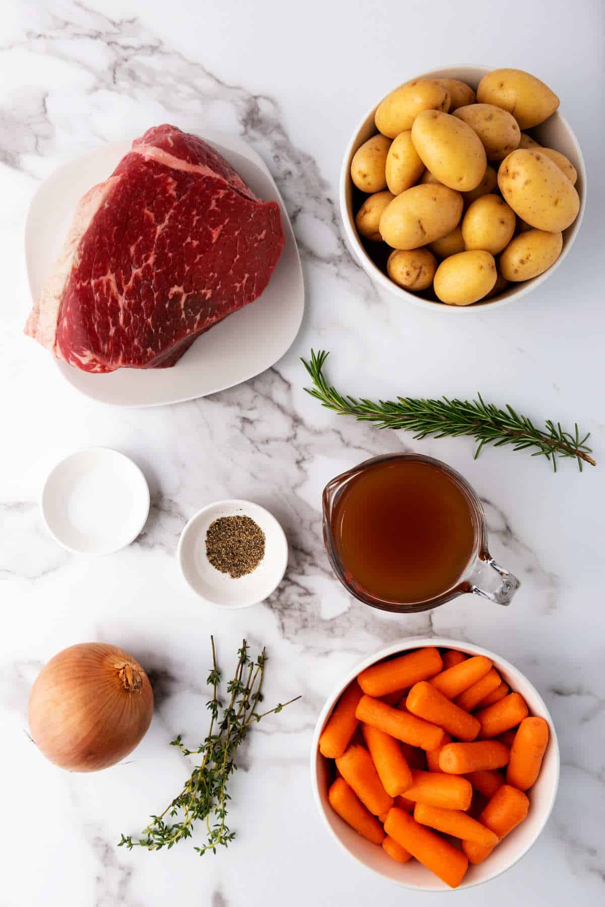 rump roast, potatoes, carrots, onion, herbs, seasonings, and broth on a white background.