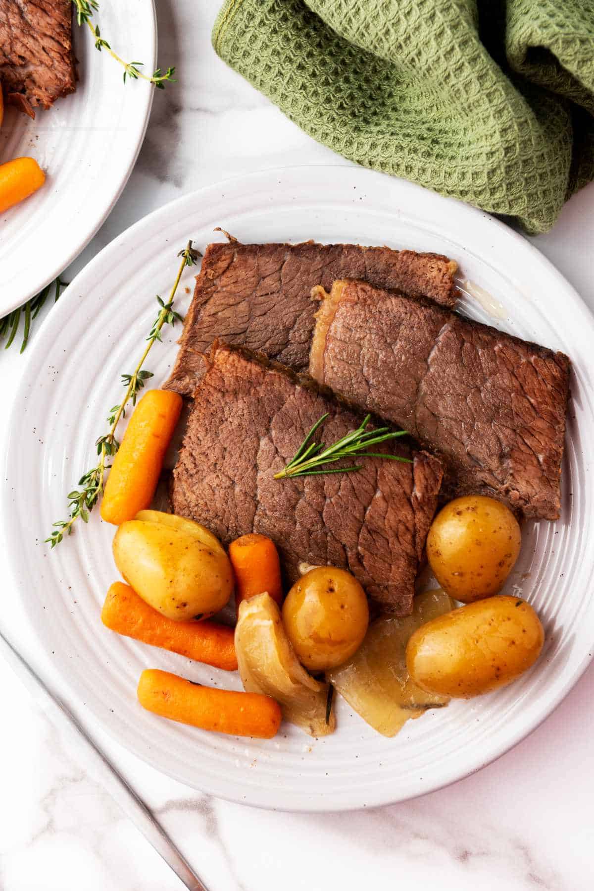 plate with slices of roast, potatoes, and carrots.