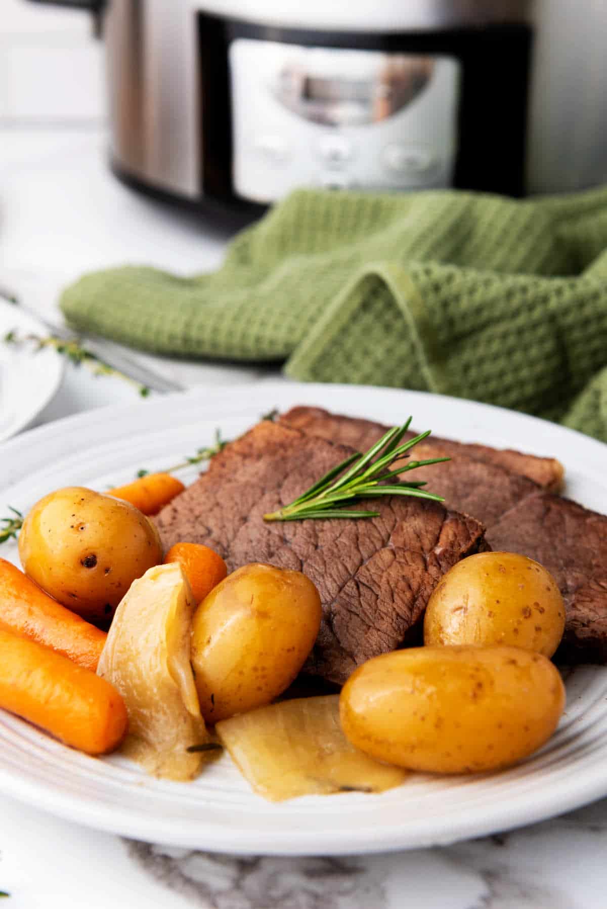 plate with slices of roast, potatoes, and carrots.