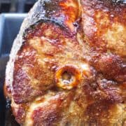 roasting pan on a grill with a double smoked ham that has a crispy glaze.