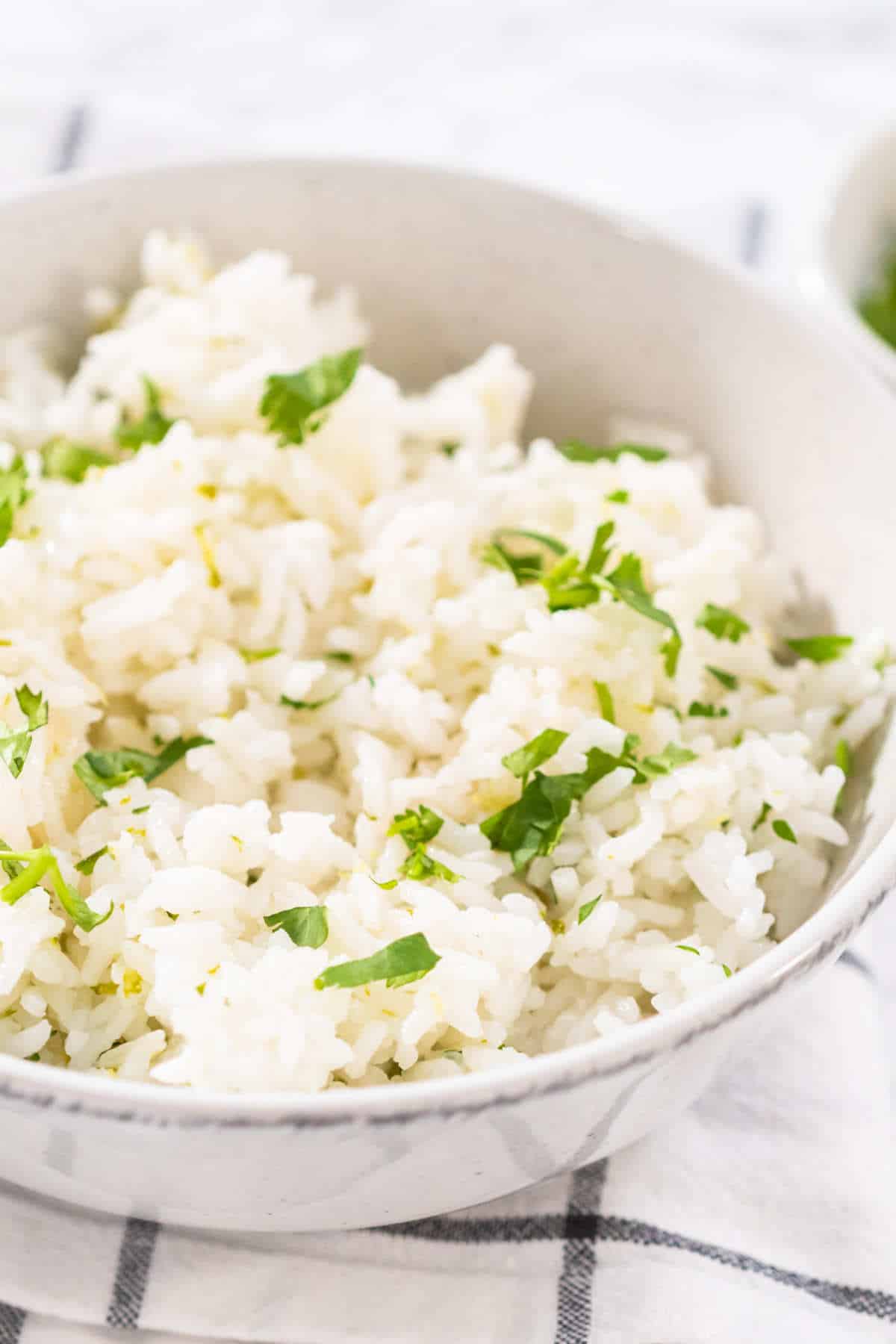 serving cilantro lime rice garnished with fresh chopped cilantro in white ceramic bowls.