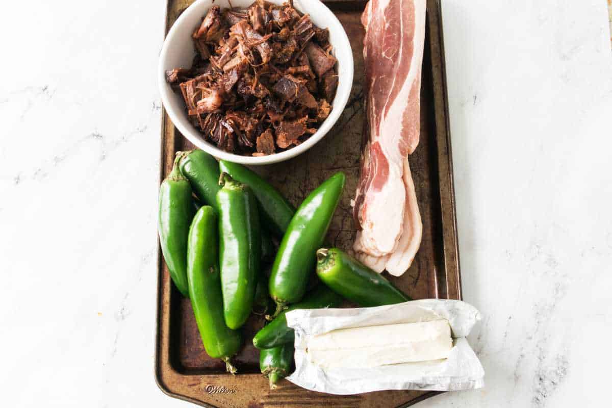 bowl of brisket, some bacon, jalapeno peppers, and cream cheese on a baking sheet for making Texas Twinkies.
