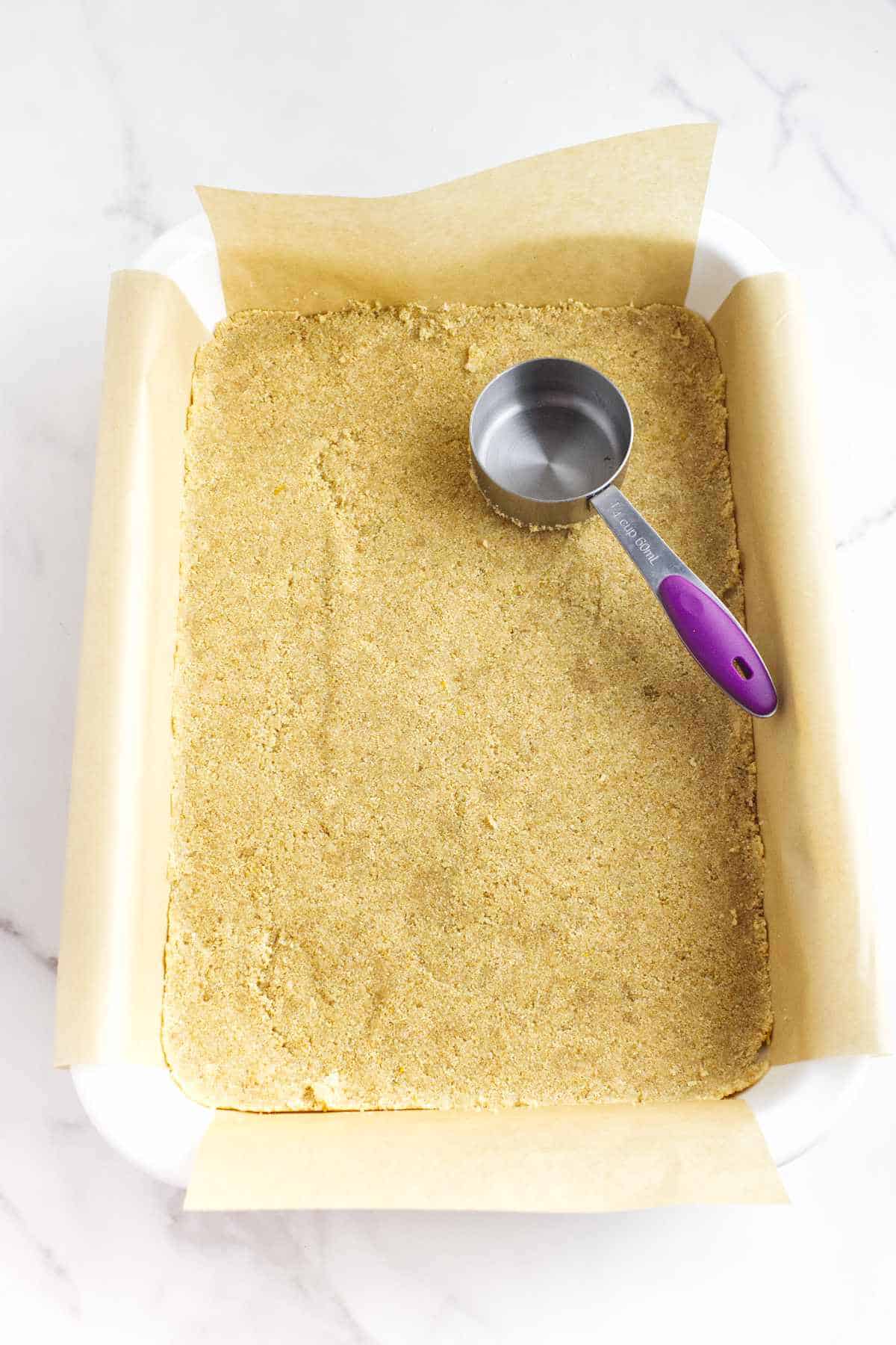 parchment paper lined baking dish with pressed graham crust.