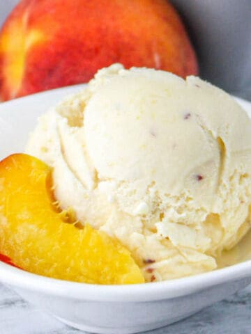 bowl of peach ice cream with slices of peach.