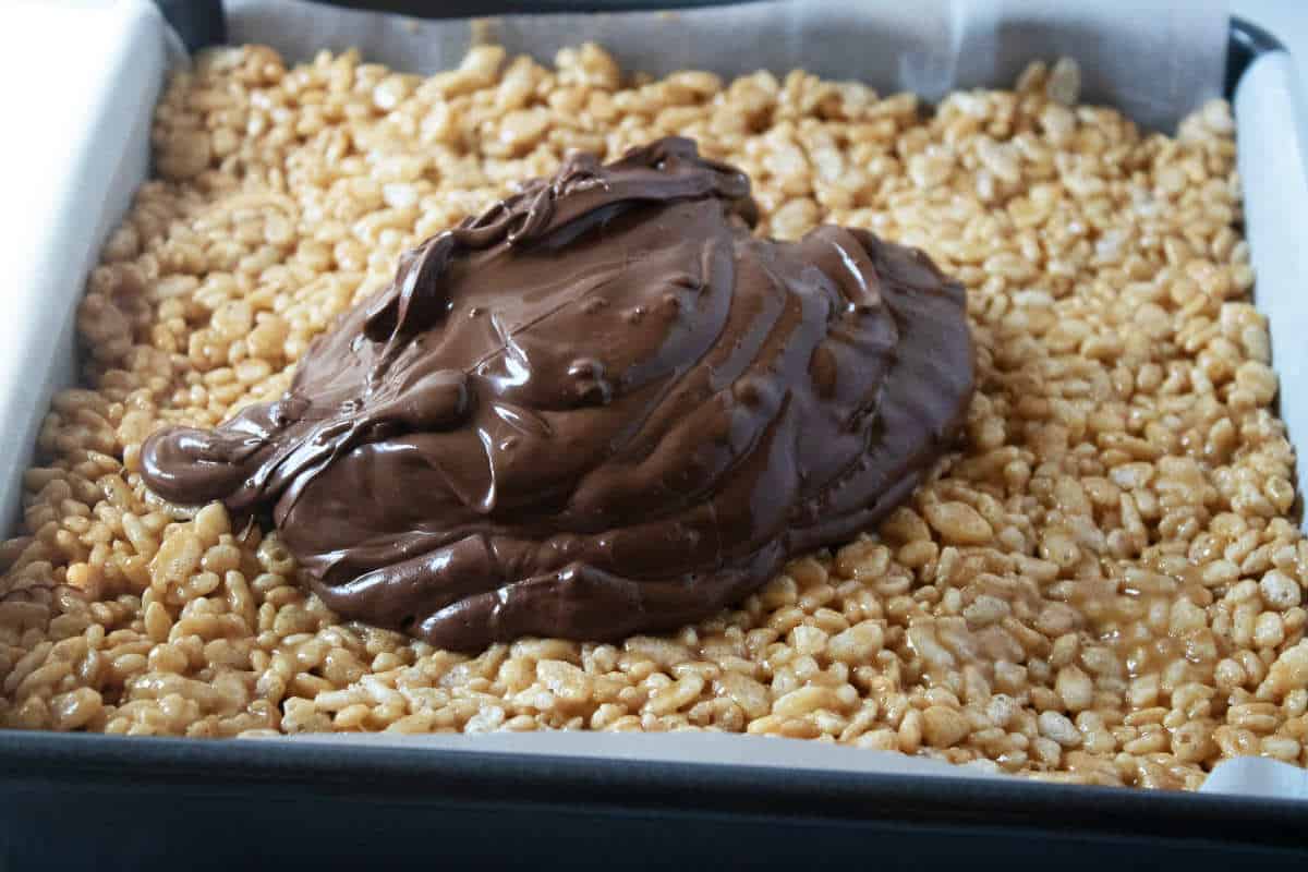 melted chocolate on top of cooled pan of cereal treats.