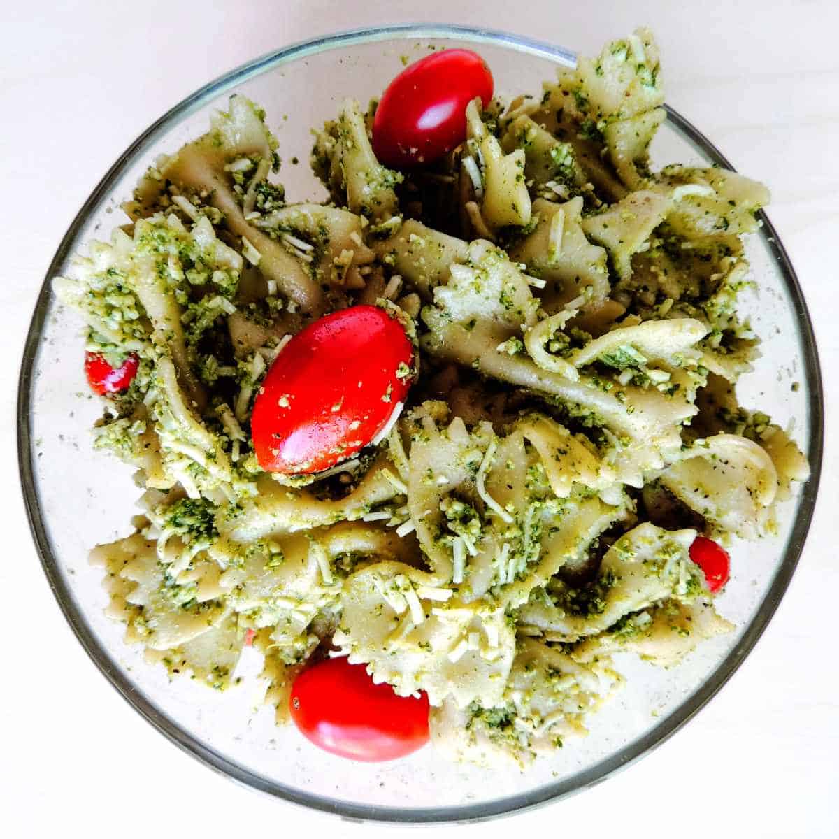 tossed pasta, tomatoes, and pesto in a bowl.