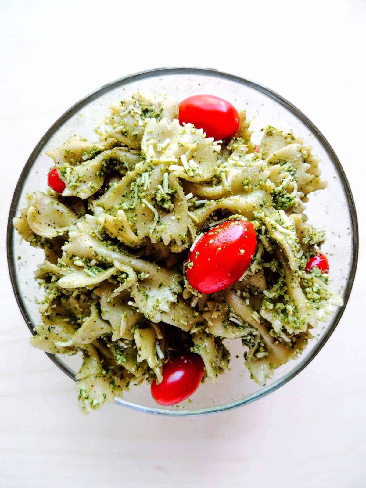 tossed pasta, tomatoes, and pesto in a bowl.