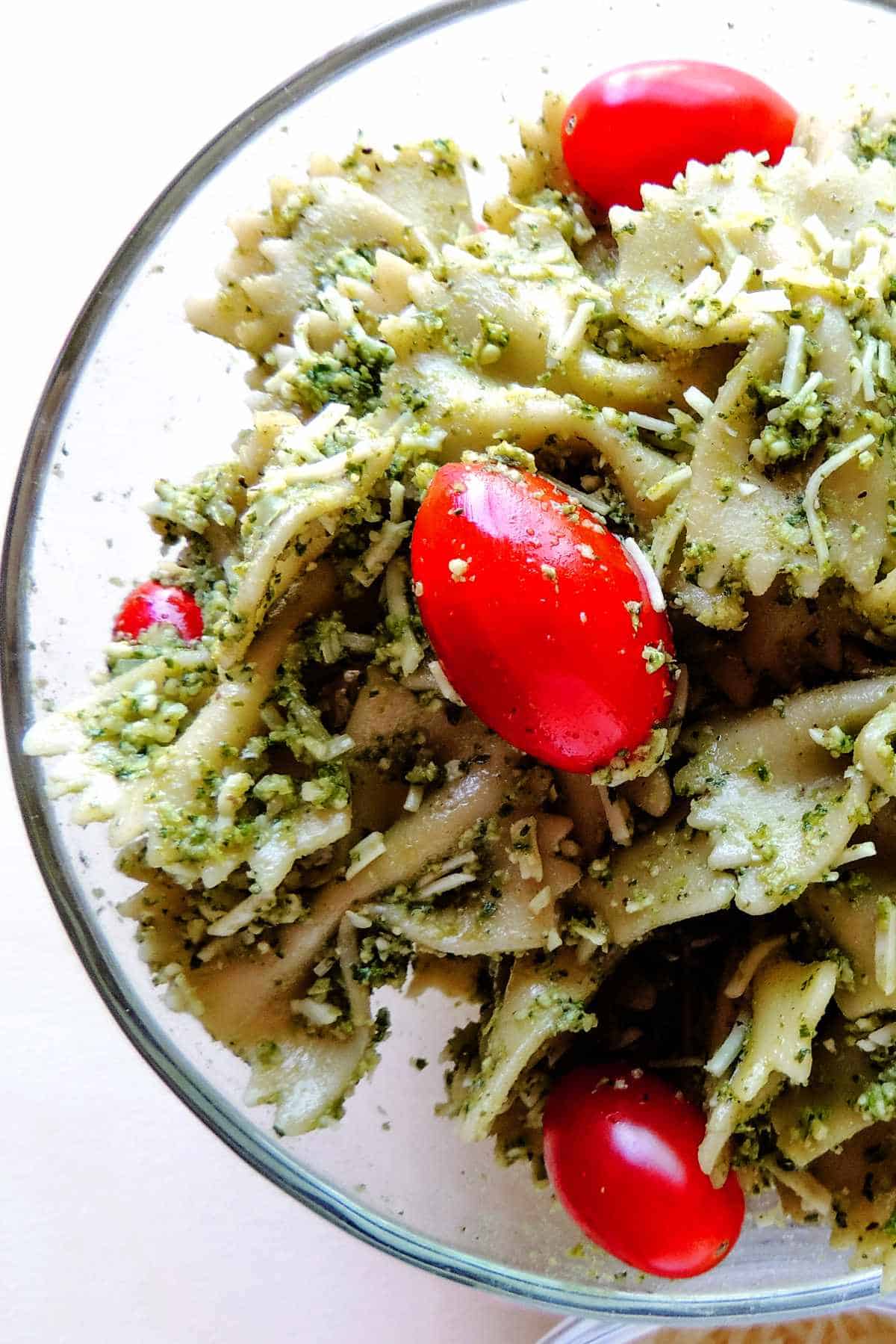 tossed bowtie pasta, tomatoes, and pesto in a bowl.
