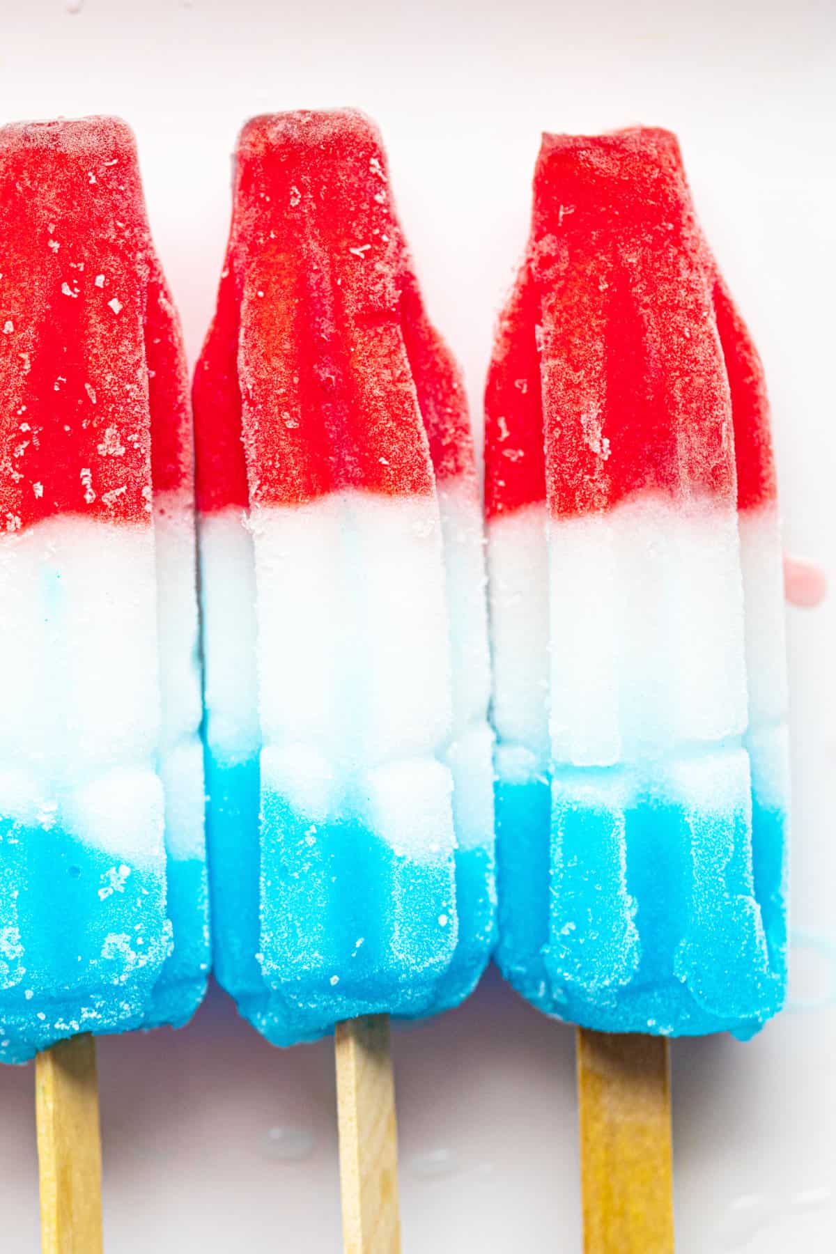 red white and blue popsicles on a tray of ice cubes, popular frozen treats.