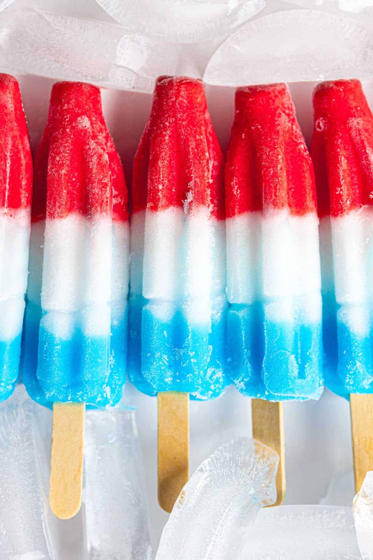 red white and blue popsicles on a tray of ice cubes.