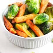 serving bowl heaped with roasted brussel sprouts and carrots.