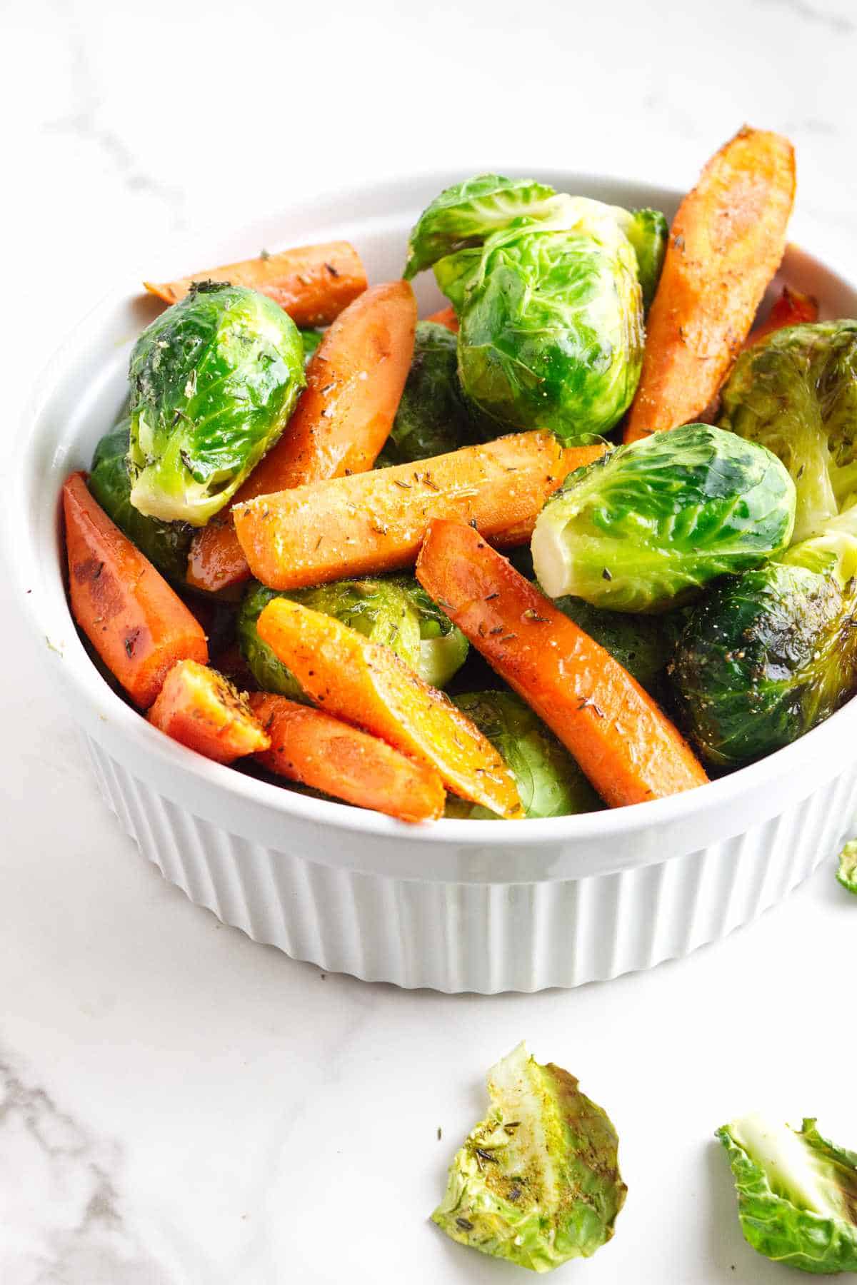 serving bowl heaped with roasted brussel sprouts and carrots.