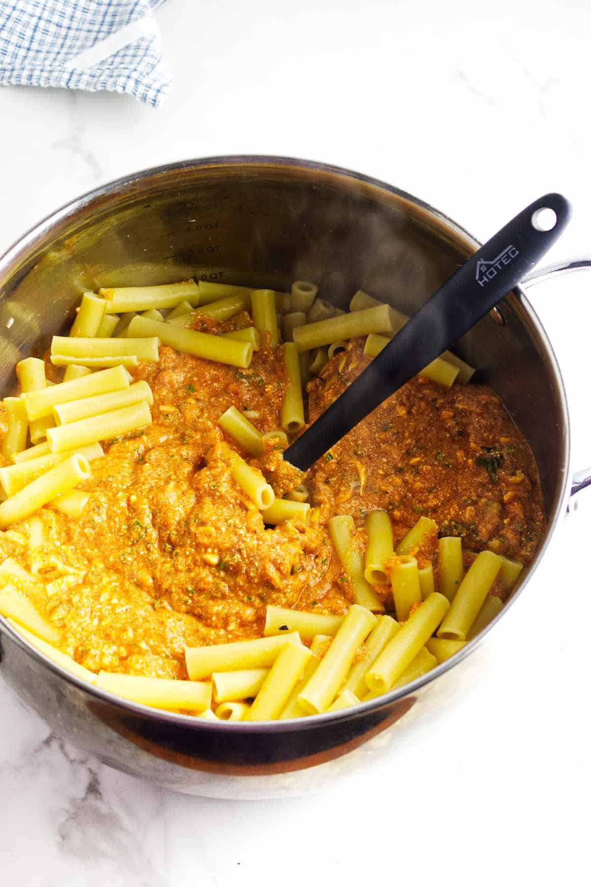pasta and cheese sauce mixed with freshly cooked ziti pasta in a bowl.