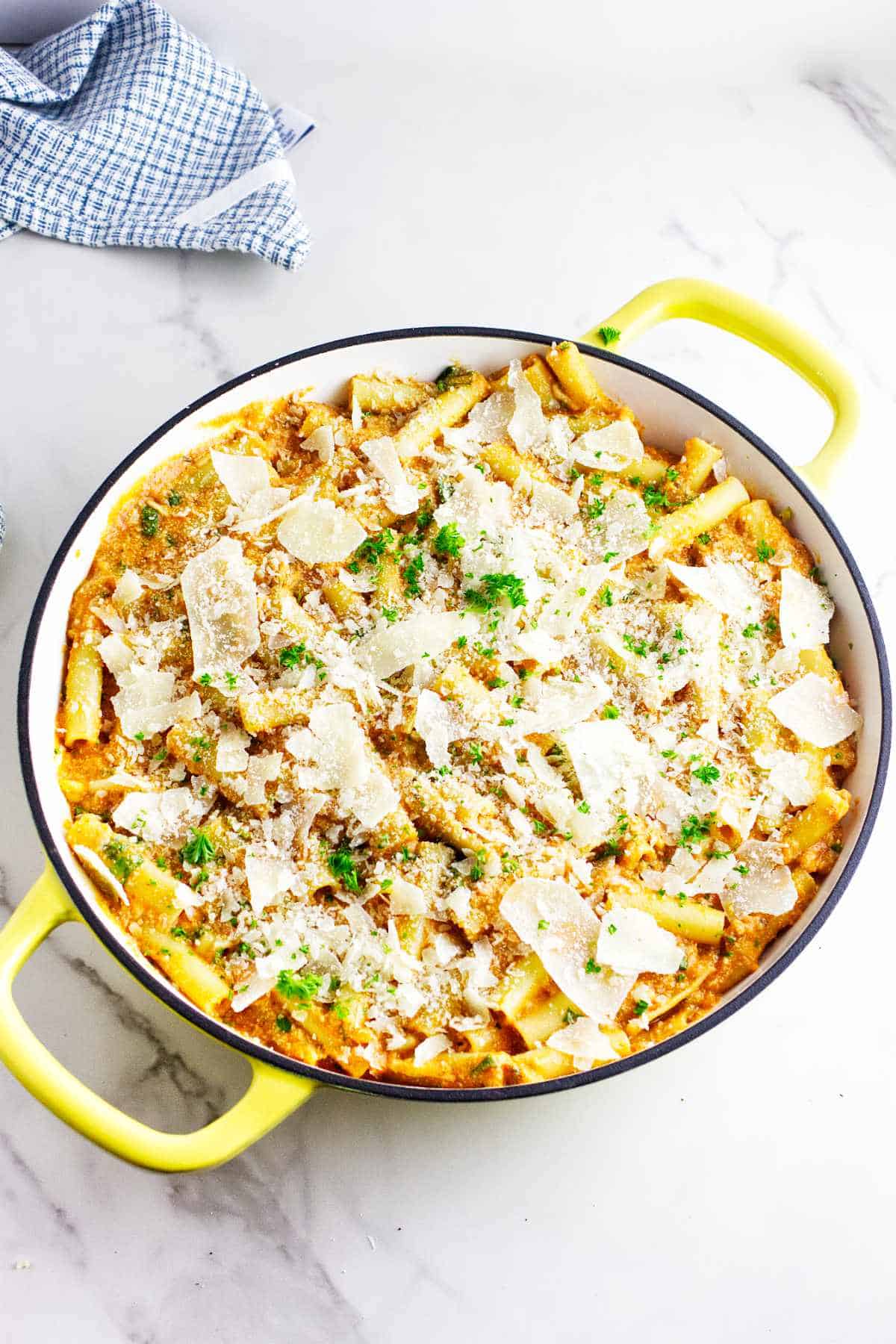shredded parmesan cheese and parsley garnishing the top of a baked ziti casserole.