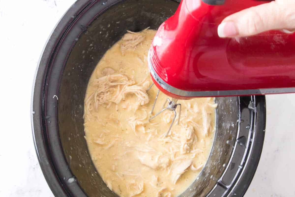 using a KitchenAid hand mixer to shred up cooked chicken with gravy.