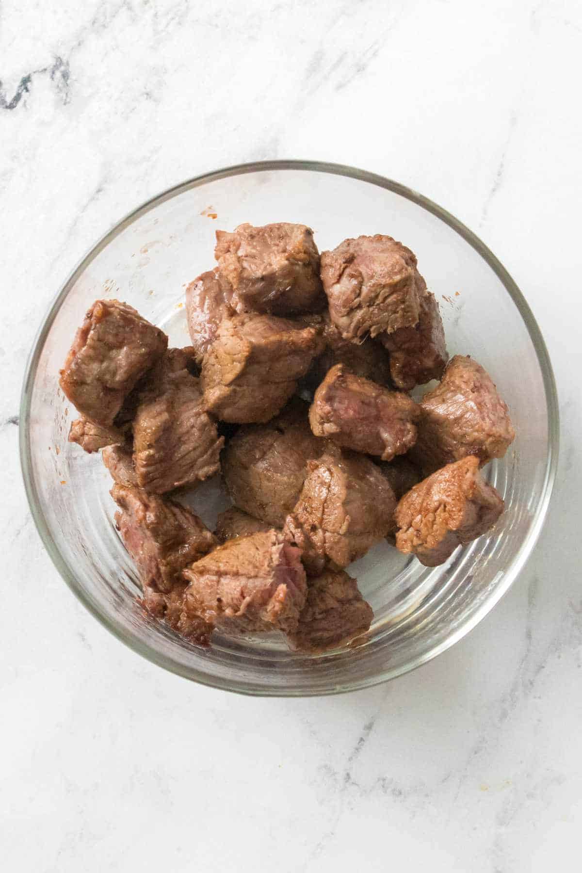 cubed seasoned cooked steak in a bowl.