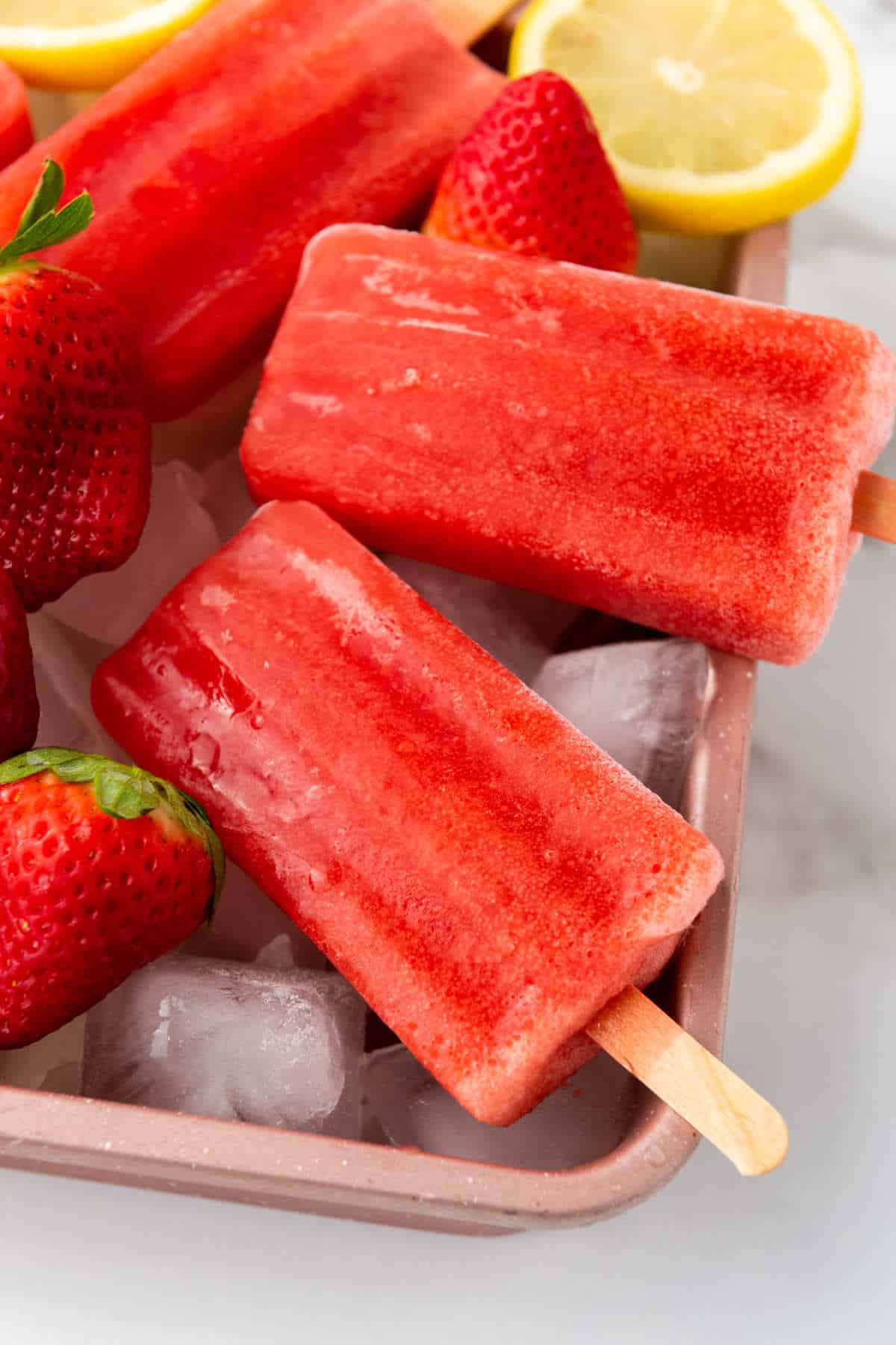 ice on a tray with frozen berry pops on top.