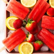 ice on a tray with strawberry popsicles on top.
