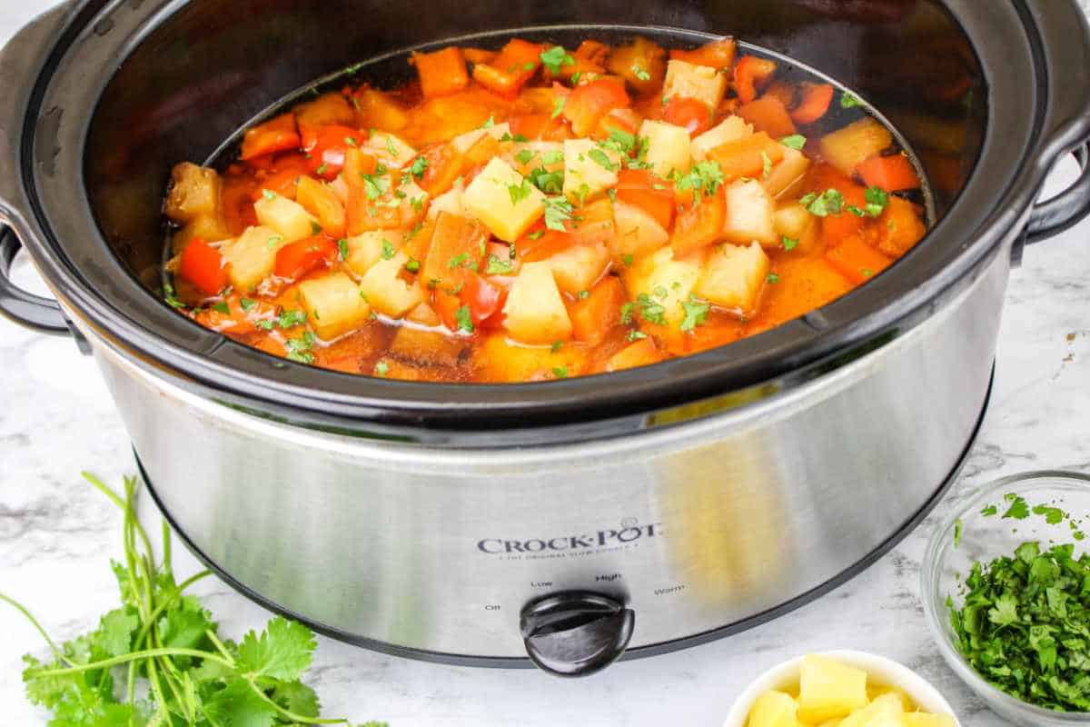 cooked chicken, pineapple, red bell pepper, and cilantro in a slow cooker.