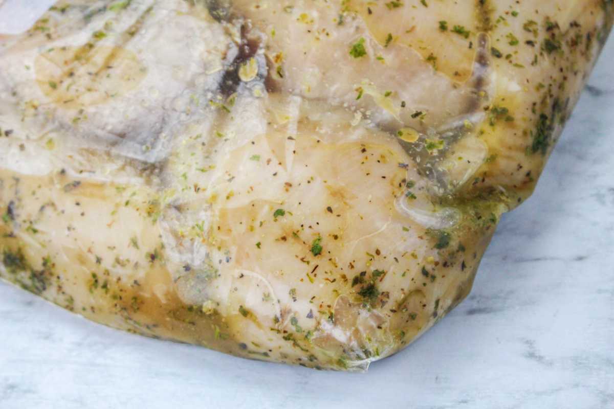 chicken chunks in a ziplock bag with marinade and herbs.